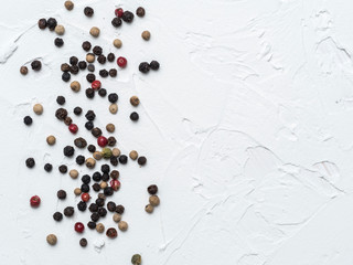 Assorted peppercorns. Medley trio colorful peppercorn on white textured concrete background with copy space. Top view or flat lay.