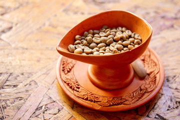 Fresh dried Robusta coffee beans in clay pot close up.
