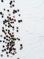 Assorted peppercorns. Medley trio colorful peppercorn on white textured concrete background with copy space. Top view or flat lay.