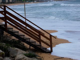 Escalera en la arena de la playa, esperando que el temporal amaine