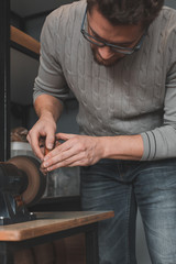 Leather craftsman sharpens knife for cutting leather on sander. Handmade concept. Concept of small business to create leather products.