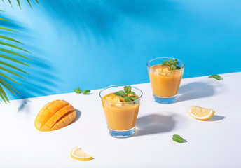 Fresh mango smoothie and ripe mango slice on color background. summer drink.
