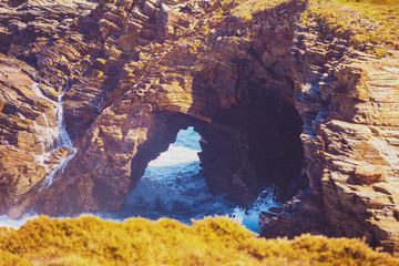 Arch in the rock. Beach Playa de Augas Santas (Beach of the Holy Waters, As Catedrais beach) during low tide at sunrise. Spain, Europe