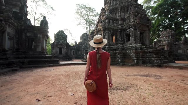 Following woman in red dress walking at sunrise in Chau Say Tevoda temple (Angkor Wat compelx) dedicated to Shiva and Vishnu with unique types of female sculptures of devatas enshrined in it. Cambodia