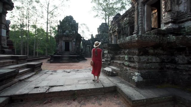 Following woman in red dress exploring the Chau Say Tevoda temple (Angkor Wat compelx) dedicated to Shiva and Vishnu with unique types of female sculptures of devatas enshrined in it. Cambodia