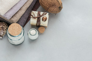 Fototapeta na wymiar Organic cosmetics with coconut oil, sea salt, towels and handmade soap on grey background