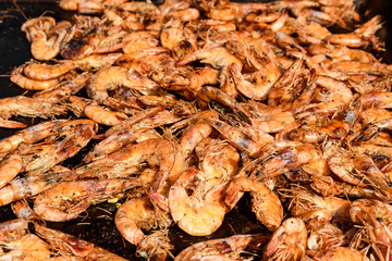 Close up of a large portion of shrimps prepared on a hot grill in display at a street food market