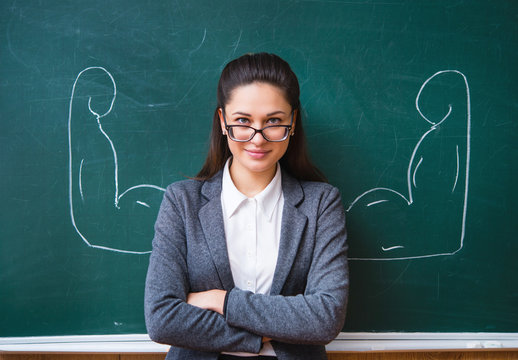 smiling teacher in the glasses near the board