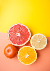 Flat lay of cut ripe juicy grapefruit, lemon and orange on yellow and orange color background. Citrus pattern.