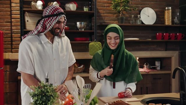 Cute young muslim couple cook together cut vegetables on kitchen smile talk at home food arab arabian arabic dinner eating emirates fresh happy healthy islam meal preparing slow motion