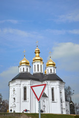road sign give way in front of the old church against the blue sky with clouds
