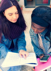 Two young women study on a bench.