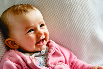 Pretty and adorable 6 month old baby girl smiling while playing with her mother.