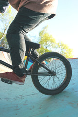 Close up of a BMX bike with a young extremals cyclist on a special ramp for tricks. Hobbies of modern youth.