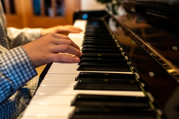 Child's hands playing the keys of a piano during Christmas.