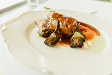 Plate of carefully prepared food, pork tenderloin confit with artichokes.