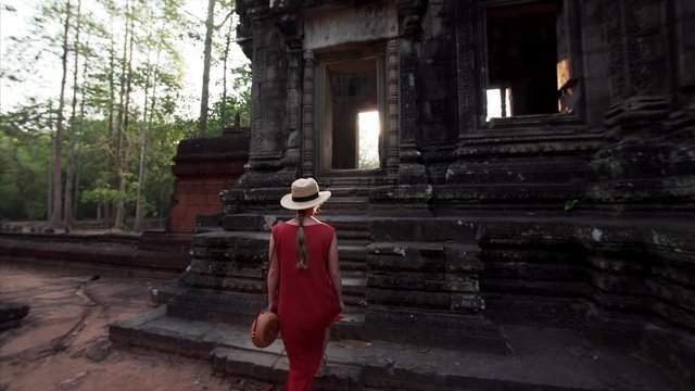 Following woman in red dress going upstairs to enter one of the buildings of Chau Say Tevoda temple dedicated to Shiva and Vishnu in Angkor Wat compelx. Sunrise. Cambodia