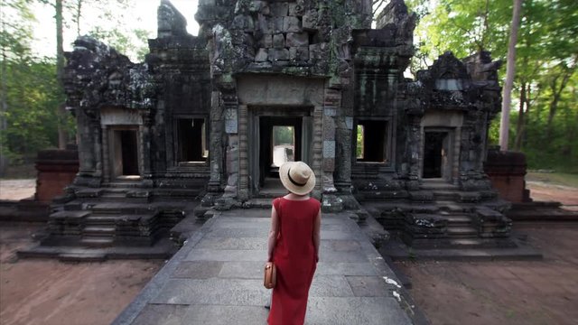 Woman in long red dress exploring the Chau Say Tevoda temple (Angkor Wat compelx) dedicated to Shiva and Vishnu with unique types of female sculptures of devatas enshrined in it. Cambodia