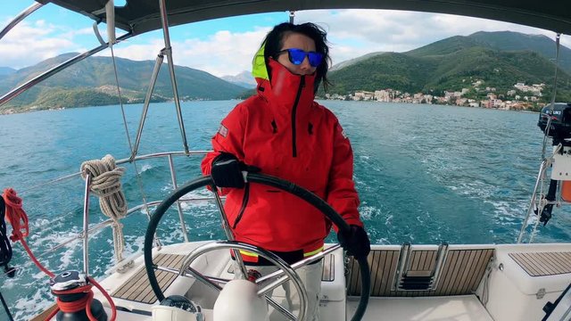 A woman is driving a yacht across a lake