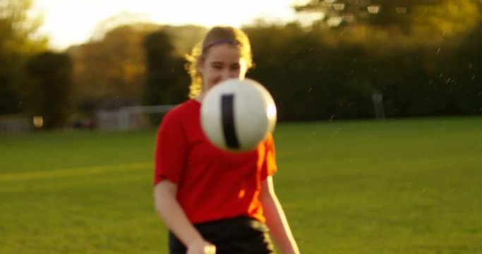 4K Young soccer player practicing her ball skills in the rain on a summer evening. Slow motion.