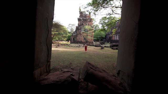 Sliding view from the window of woman walking near Prasat Suor Prat, a series of twelve towers in Angkor Wat complex, made from rugged laterite and sandstone. Cambodia
