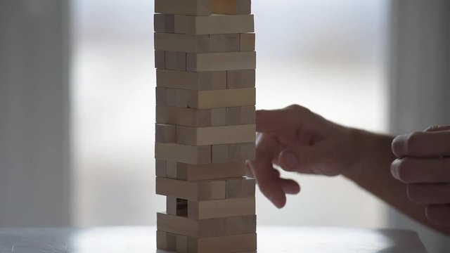 Closeup photo of man playing wooden blocks tower game