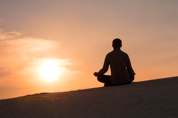 man in the lotus position at sunset