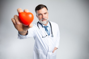 healthcare and medicine concept - mature doctor holding red heart.