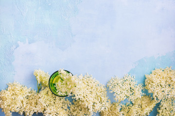 Elderflower cordial syrup with lemon and  elder branches on a rustic blue  wooden table. Top view,...