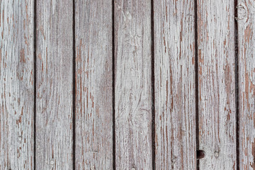 A whitewashed wooden surface worn out due to weather. Planks painted white. The texture of the wooden board.