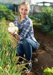 Female holding fresh onion at garden