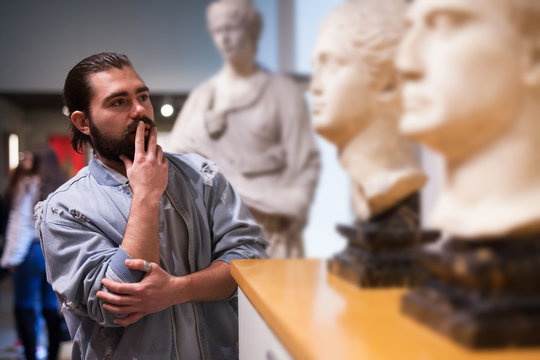 Man looking at stone architectural elements in historical museum hall