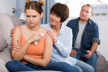 Parents are comforting the upset adult daughter on sofa