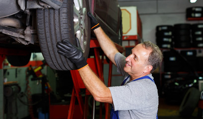 Mechanic installing car wheel after repair of balancing