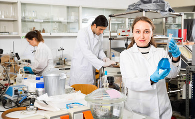 Young female lab technician working with reagents in test tubes during chemical experiment