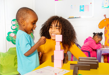 Excited little boy in nursery about block tower
