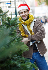 Portrait of joyful  man choosing toys and Christmas tree at fair