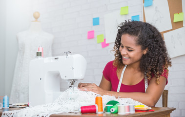 Portrait of beautiful black designer woman using sewing machine in tailer fabric fashion small business workshop. Young owner entrepreneur creative girl working textile business concept