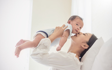Portrait of mother lifting and playing with newborn baby, baby talking to mother. Health care...