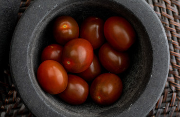 Cherry tomatoes mini Kumato. In stone mortar. Rustic appearance.