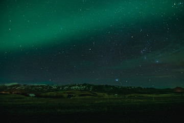Fototapeta premium Northern Lights in cold Icelandic nights, near waterfall Seljalandsfoss