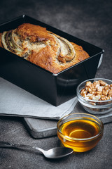 Banana bread with nuts, honey and mint on a dark background.