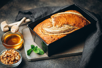 Banana bread with nuts, honey and mint on a dark background.