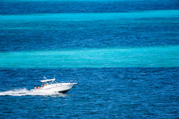 Bote deportivo navegando por el mar caribe con personas disfrutando de un día soleado en el mar caribe de Cancin, Mexico, contraste de colores azul turquesa