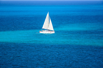 Velero de dos velas navegando en el mar caribe con contraste colores azul turquesa, Cancun, Mexico 