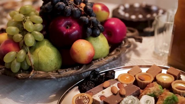 Close up for the traditional table with apples, grapes, pears and different oriental sweets with nuts, food and celebration concept. Stock. Delicious dishes with fruits and sweets.