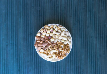 Obraz na płótnie Canvas Healthy food. Nuts mix assortment on stone texture top view. Collection of different legumes for background image close up nuts, pistachios, almond, cashew nuts, peanut, walnut. image