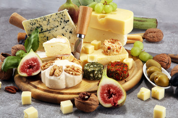 Cheese plate served with figs, various cheese on a platter on wood