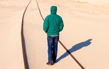 man stands on the railway in the sand