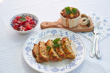 Close up Picture on the traditional baked czech spring dish, kind of salt cake or quiche, made from eggs, smoked ham, bread, pork meat and parsley, served on rustic plate with fresh tomato salad.